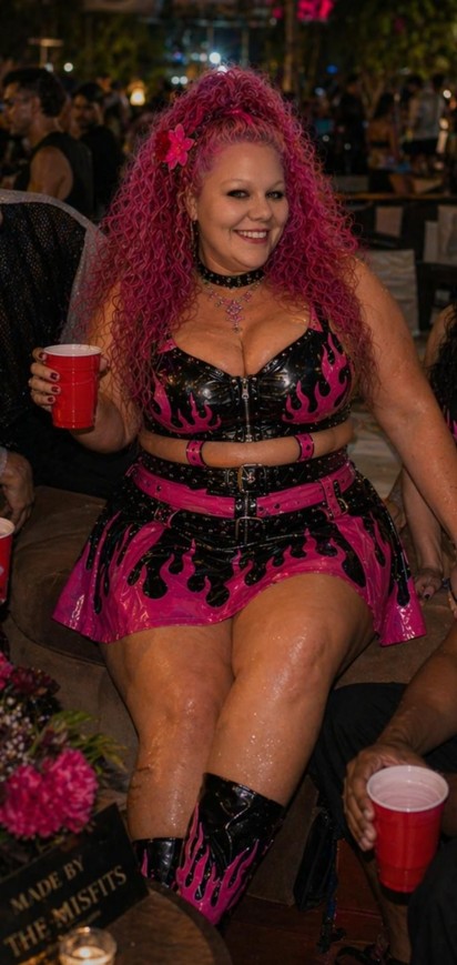 Woman in pink and black vinyl skirted outfit having fun drinking at a music concert
