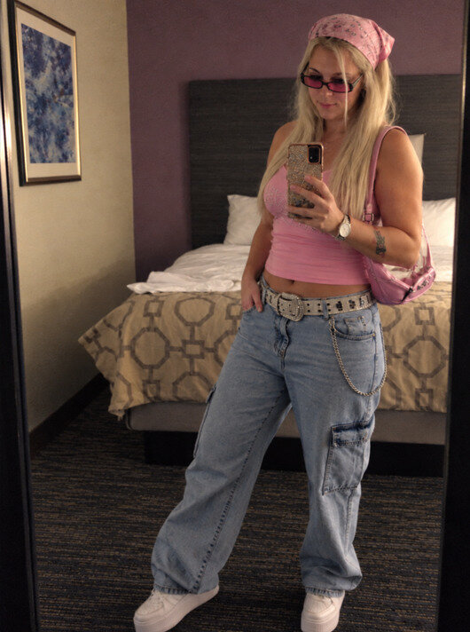 Woman in a motel room posing in a Y2K outfit.