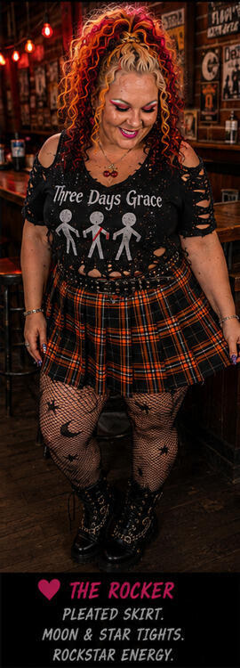 Woman in plaid skirt and band tee modeling in a bar setting.